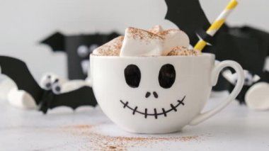 4k zoom in out Painted white cup scary jacks face with marshmallows Hot chocolate cacao drink DIY for kids. Halloween home activities Holiday art children craft Handmade decorations home Idea for art
