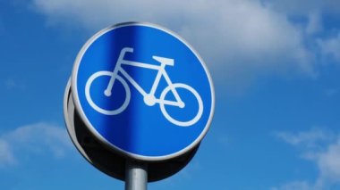 Round road sign depicting white bicycle on blue background, meaning mandatory bike path for cyclists against blue sky background. Blue round sign on bike path pole. Bike path