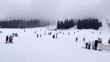 Kışın dağlarda yokuş aşağı kayak yapan kayakçılar. Kayak alanının yukarıdan görünüşü. Tepeden kayakçılar ve snowboardcular iniyor. Karpatlar 'ın dağlık kayak merkezinde kayakçılar ve asansörler, görkemli karlı kış.