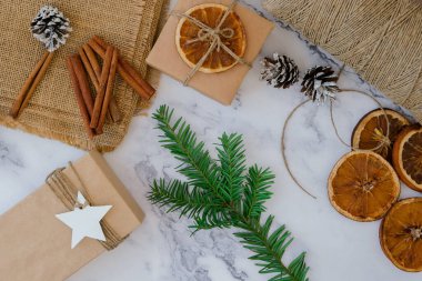 Yeni yıl hediyeleriyle kutu hazırlayan kadın, el işi kağıdına sarılmış ve köknar dallarıyla süslenmiş. Tatiller ve Hediyeler konsepti. El yapımı çevre dostu alternatif yeşil Noel sunar sıfır atık sürdürülebilir yaşam tarzı Top view yatıyordu