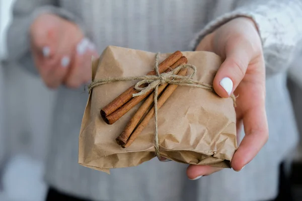 Woman giving Box with New Year\'s gifts, wrapped in craft paper and decorated with cinnamon sticks. Holidays and Gifts concept. Handmade Eco friendly alternative green Christmas presents zero waste Sustainable lifestyle