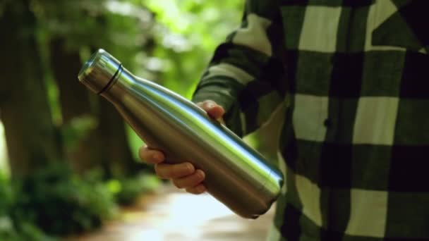 水ボトルを保持認識できない女性の手のクローズアップ 公園で再利用可能なスチール熱水ボトル 持続可能なライフスタイル プラスチックフリーゼロ廃棄物フリー生活 緑の環境保護へ — ストック動画