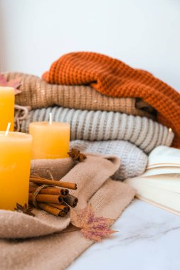 Merhaba güz, kış tatilini pencerenin kenarındaki evde kutluyoruz Şükran Günü atmosferinde Şükran Günü yaprakları, baharatlar ve sıcak sarı ışıkta örülmüş sıcak süveter üzerine mum. Pencerenin dışında Seçici Odaklanma Yağmuru