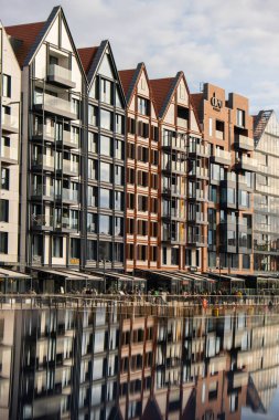 Old Town 'daki Motlawa Nehri üzerindeki modern binalar. Soyut yapı. Motlawa Nehri 'nde yaratıcı fotoğraf turizmi. Granary Adası cam pencerelerinde yansımalı yeni apartmanlar mimarisi