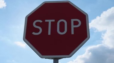 Red stop sign on metal pole on street. Road attention sign on cloudy background. Outdoors