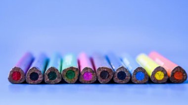 4k, pastel kalemlerin arka planına yakınlaştır. Mavi arka planda renkli kalemler. Kapatın. Satıra yerleştirilen çeşitli renkli kalemlerin üst görünümü