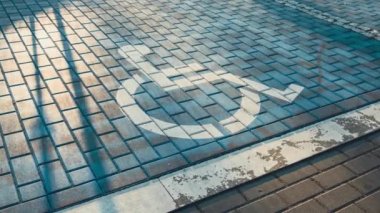 Engelli otoparkından 4k zum yap. Engelli park yerleri için ayrılmış park levhası koyu asfalta boyanmış mavi park levhası tekerlekli sandalye işaretli bir park yerinde engelli işareti