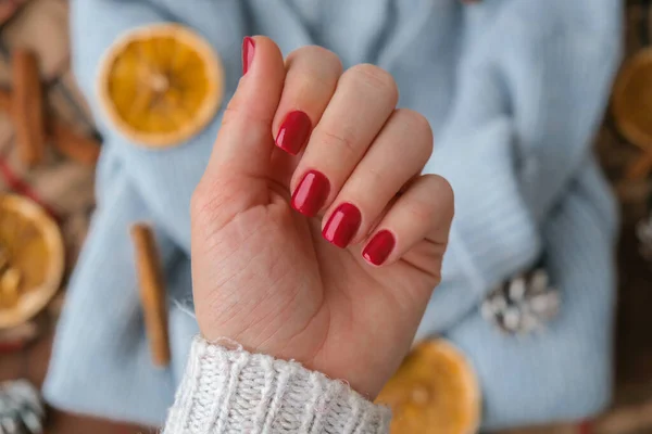 Woman manicured hands, stylish red nails, copy space. Blue sweater Closeup. Winter or autumn style of nail design concept. Beauty treatment. Fall nails
