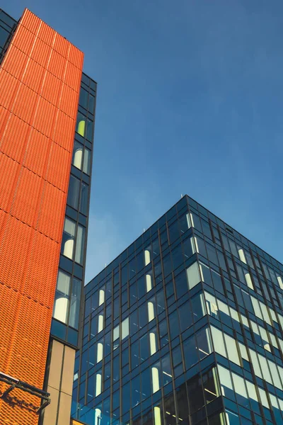 Modern office building exterior with glass facade on clear sky background. Transparent glass wall of office building with orange decoration. Element of facade of modern European building Commercial