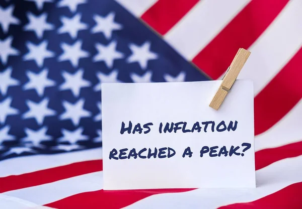 The National Flag of USA. American Flag and paper note message text HAS INFLATION REACHED A PEAK. global hunger, inflation, high prices, increasing living expenses and poverty, financial crisis, food