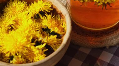 Karahindiba çiçeği cam çaydanlıkta sağlıklı çay ve masada cam bardak. Bahçe yakınlarındaki yaz gününde taze karahindiba çiçeklerinden dökülen lezzetli bitkisel çay. Yeşil açıklık Sıcak karahindiba çayı