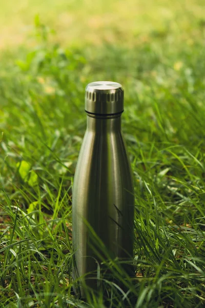 Water bottle. Reusable steel thermo water bottle on green grass. Sustainable lifestyle. Plastic free zero waste free living. Go green Environment protection. Health-conscious. Steel thermo water