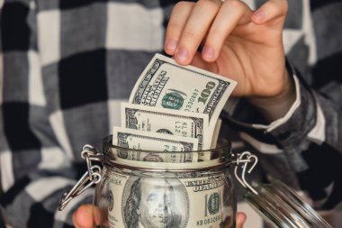 Dollar banknote saving money in glass jar. Unrecognizable woman moderate consumption and economy Collecting money. Tips. Business, finance, saving, banking and people concept. Extra money, passive