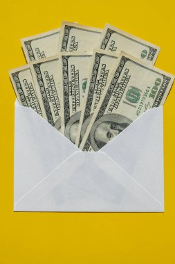 Bir dolarlık banknot, sarı arka plan fotokopi alanındaki zarf içinde tasarruf ediyor. Tüketim ve ekonomi para topluyor. Bahşiş. İş, finans, tasarruf, bankacılık ve insan konsepti. Ekstra para, pasif