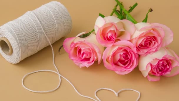 Увеличьте Нежные Розовые Розы Катушкой Белой Хлопковой Веревки Форме Сердца — стоковое видео