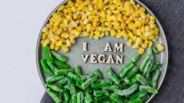 4k zoom out I am VEGAN metin in plaka. Vejetaryenlik, vejetaryen sağlıklı yaşam tarzı yeşil fasulye sarı mısır. Sağlıklı beslenme vejetaryeni. Tahta harfler.