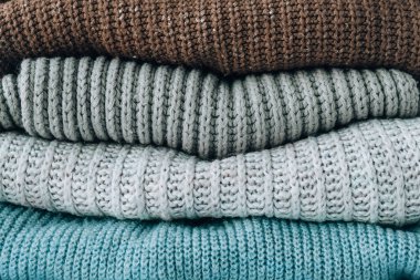 Sıcak örülmüş bir kazak yığını. Eski moda süveterler. Turuncu ve mavi renkler. Konforlu hygge konsepti Boşluğu kopyala Sonbahar kış sezonu