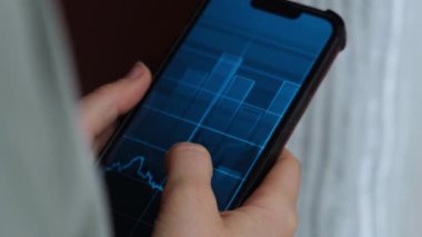 Kadın eli telefonu tutuyor, borsa grafiğini kontrol ediyor ve güvenlik değiş tokuşuna yatırım yapıyor. Telefonu tutan kadın, hisse senedi ekranını göster. Borsa yatırım kavramı Muhasebe