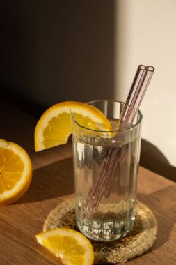 Glass of water with fresh lemon juice with Reusable glass Straws Detox cold tonic water with sunny lemon slices Low-waste lifestyle Eco-Friendly Drinking Straw Set with cleaning brush. Zero waste
