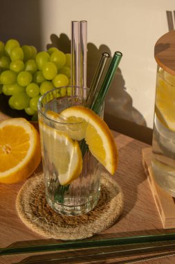 Bir bardak taze limon suyu ve yeniden kullanılabilir cam kamış detoks soğuk tonik su ve güneşli limon dilimleri düşük atık yaşam tarzı Eko-Dost Canlısı Seti temizlik fırçası ile birlikte. Sıfır atık