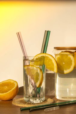 Bir bardak taze limon suyu ve yeniden kullanılabilir cam kamış detoks soğuk tonik su ve güneşli limon dilimleri düşük atık yaşam tarzı Eko-Dost Canlısı Seti temizlik fırçası ile birlikte. Sıfır atık