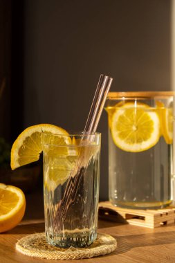 Glass of water with fresh lemon juice with Reusable glass Straws Detox cold tonic water with sunny lemon slices Low-waste lifestyle Eco-Friendly Drinking Straw Set with cleaning brush. Zero waste