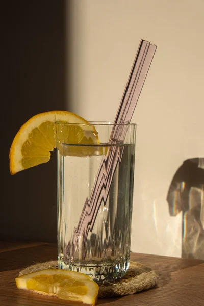 Glass of water with fresh lemon juice with Reusable glass Straws Detox cold tonic water with sunny lemon slices Low-waste lifestyle Eco-Friendly Drinking Straw Set with cleaning brush. Zero waste