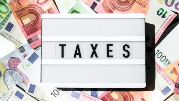 Zoom Ven Lightbox Deska Slovem Taxes Černými Písmeny Kolem Eurobankovek — Stock video