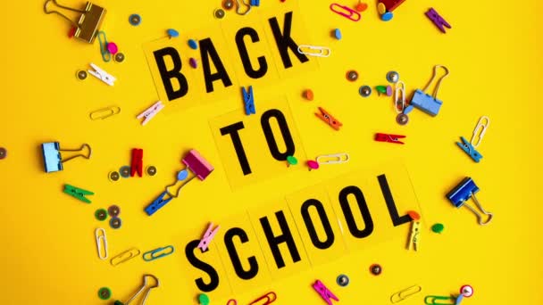 Kズームアウト色の紙クリップ 黄色の背景に服ピン 学校のテキストに戻る 学校に戻る碑文 — ストック動画