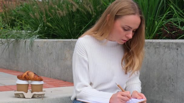 Estudante Jovem Estuda Com Caderno Parque Beber Café Comer Croissants — Vídeo de Stock