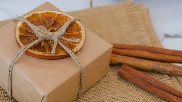 Woman making Box with New Year\'s gifts, wrapped in craft paper and decorated with dry orange slices. Holidays and Gifts concept. Handmade Eco friendly alternative green Christmas presents zero waste Sustainable lifestyle