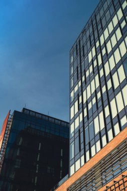 Gökyüzü arka planında cam cepheli modern ofis binası. Ofis binasının şeffaf cam duvarı, turuncu süslemeli. Modern Avrupa binasının dış cephesi