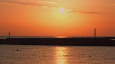 Güneş ışığının günbatımında deniz yüzeyine yansıması. Turuncu ve altın rengi mavi gökyüzü. Manzaralı altın deniz. Denizden dramatik sarı güneş geliyor. Muhteşem yaz manzarası