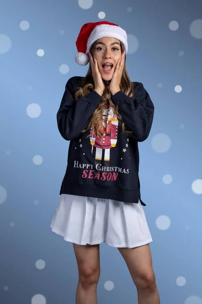 Porträt einer überraschten jungen Lateinerin mit Weihnachtspullover und Nikolausmütze — Stockfoto