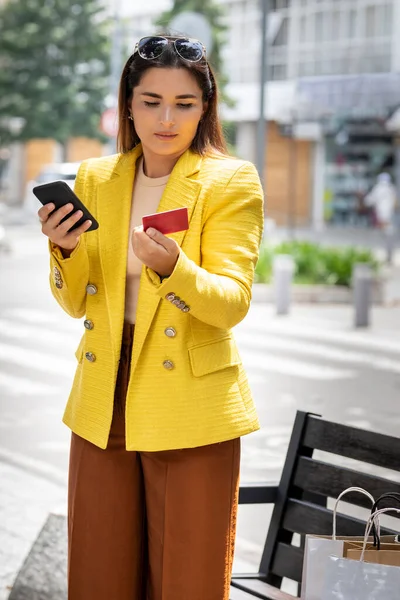 Tânăra femeie executivă pe stradă cu cardul ei de credit în mână și vorbind pe telefonul mobil — Fotografie, imagine de stoc