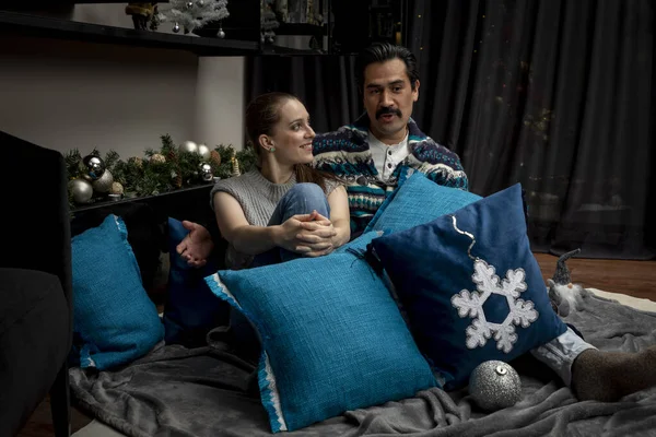 Junges verliebtes Paar in der Weihnachtsnacht mit Kissen im Wohnzimmer umarmt — Stockfoto