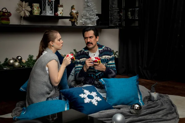 Junges Paar plaudert fröhlich bei Kaffee im Wohnzimmer in einer Weihnachtsnacht mit Kissen und Weihnachtsdekoration — Stockfoto