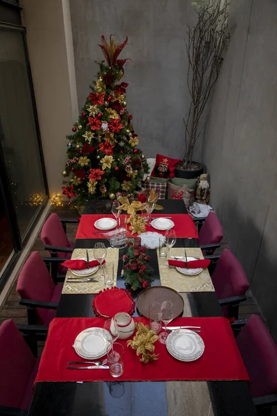 Bela mesa com decorações vermelhas de Natal em um terraço com uma árvore de Natal ao lado dele — Fotografia de Stock