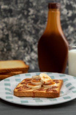 Ön planda muz ve kahve ile kızarmış ekmek.