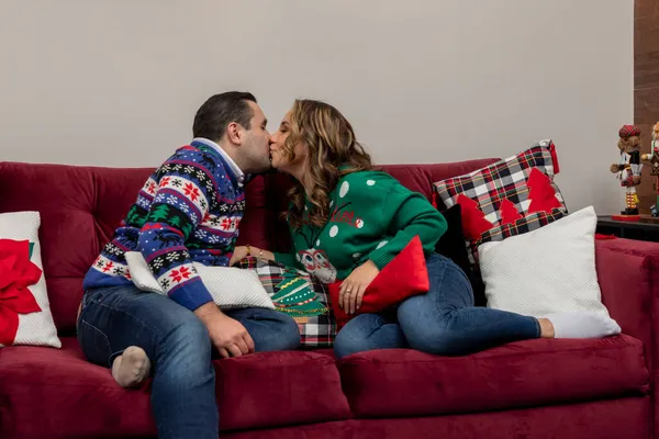 Paar küsst sich an Heiligabend im Wohnzimmer, Kissen mit weihnachtlichem Design — Stockfoto