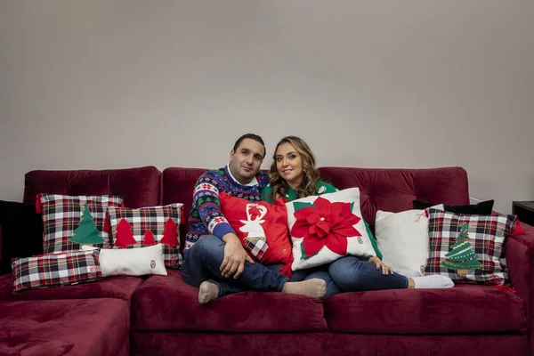 Paar im Weihnachtspullover auf dem heimischen Sofa mit Weihnachtskissen und Platz für Text — Stockfoto