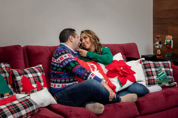 Frau blickt ihren glücklichen Mann in einer Weihnachtsnacht im Sessel mit Weihnachtsdekoration an — Stockfoto