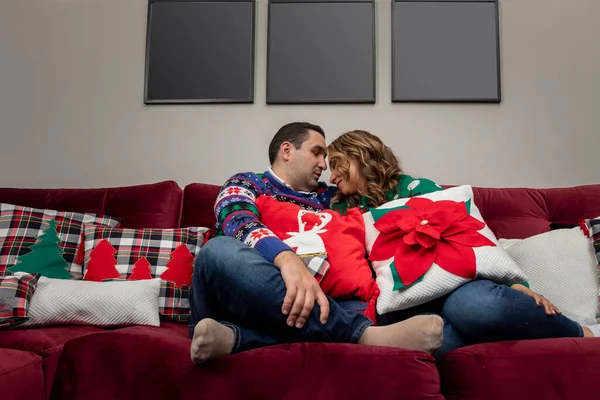 Glückliches Paar sitzt im Sessel mit Bildern an der Wand für Foto-Nominierung, Weihnachtsthema — Stockfoto