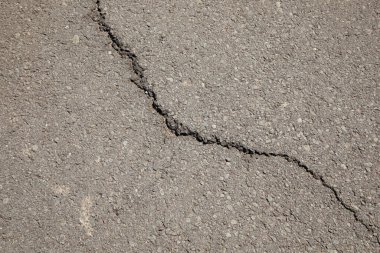 Gri asfalt arkaplan ve ortasında bir çatlak olan doku