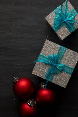 kırmızı küreler ile dikey Noel arkaplanı ve mavi yay ve metin için boşluk ile gümüş hediyeler