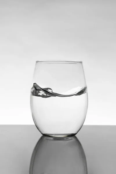 Kristályüveg mozgó vízzel és fehér háttérrel szürke gradienssel — Stock Fotó