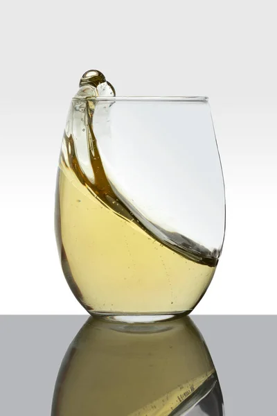Hareket eden beyaz şaraplı kristal cam dalgalar yapıyor ve beyaz zemin — Stok fotoğraf
