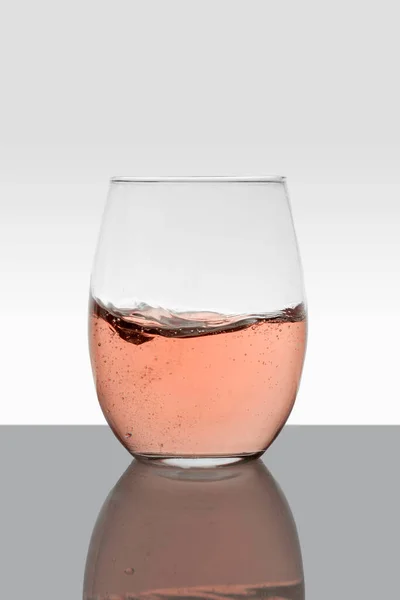 Üveg rózsa bor mozgásban és fehér színű háttér — Stock Fotó
