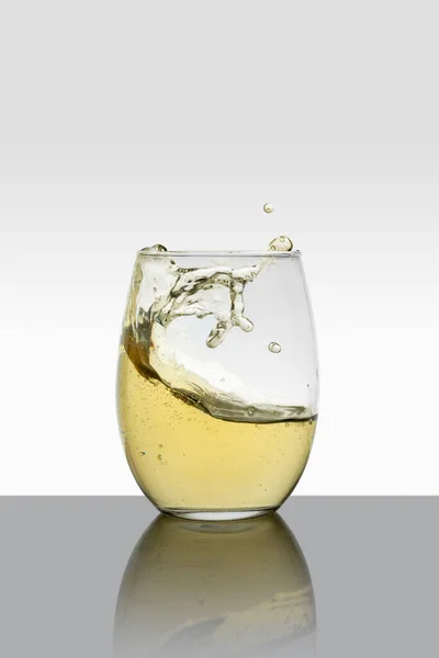 Kristallglas mit beweglichen Weißweinwellen und weißem Hintergrund — Stockfoto
