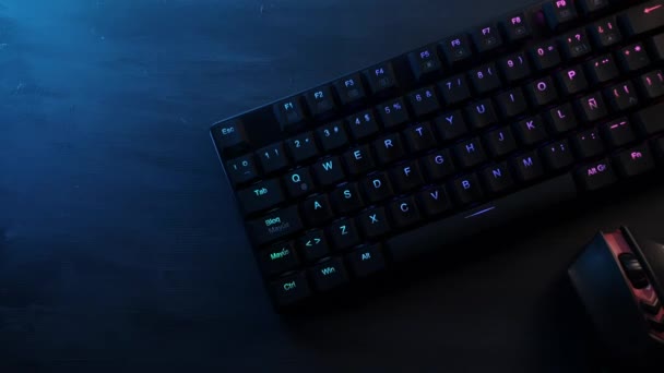 Teclado mecânico com iluminação rgb em uma mesa de madeira cinza e um mouse de jogo — Vídeo de Stock